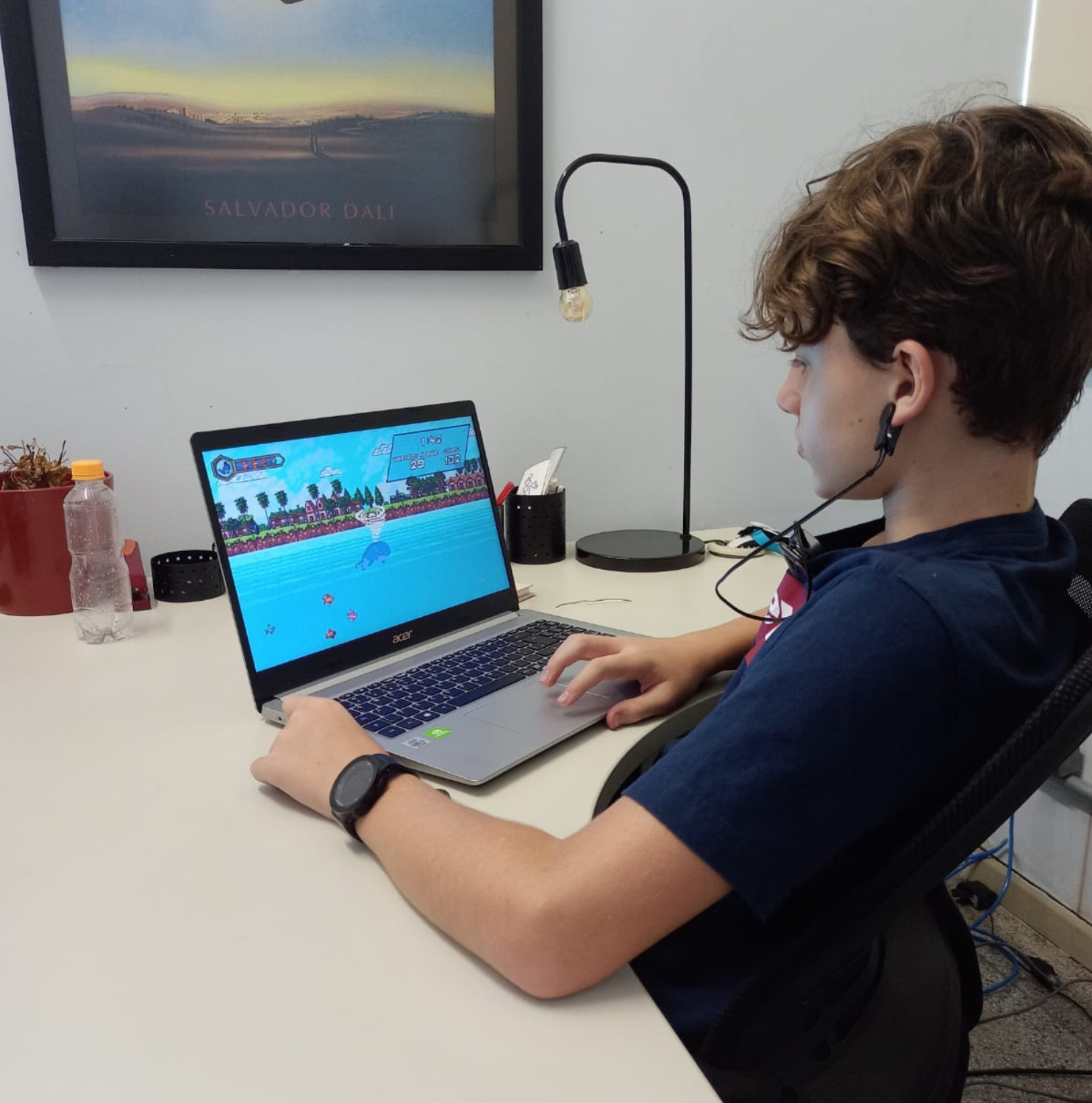 Criança jogando Keep Ocean com sensores de biofeedback - relógio no pulso e fones de ouvido conectados